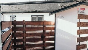 Ein verschlossener Eingang mit Holzzaun und einem weißen Gebäude mit der Nummer 306.
