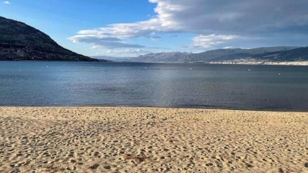 Ein Strand mit blauem Himmel und Bergen im Hintergrund.