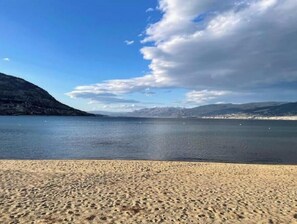 Una playa con cielo despejado y montañas al fondo.