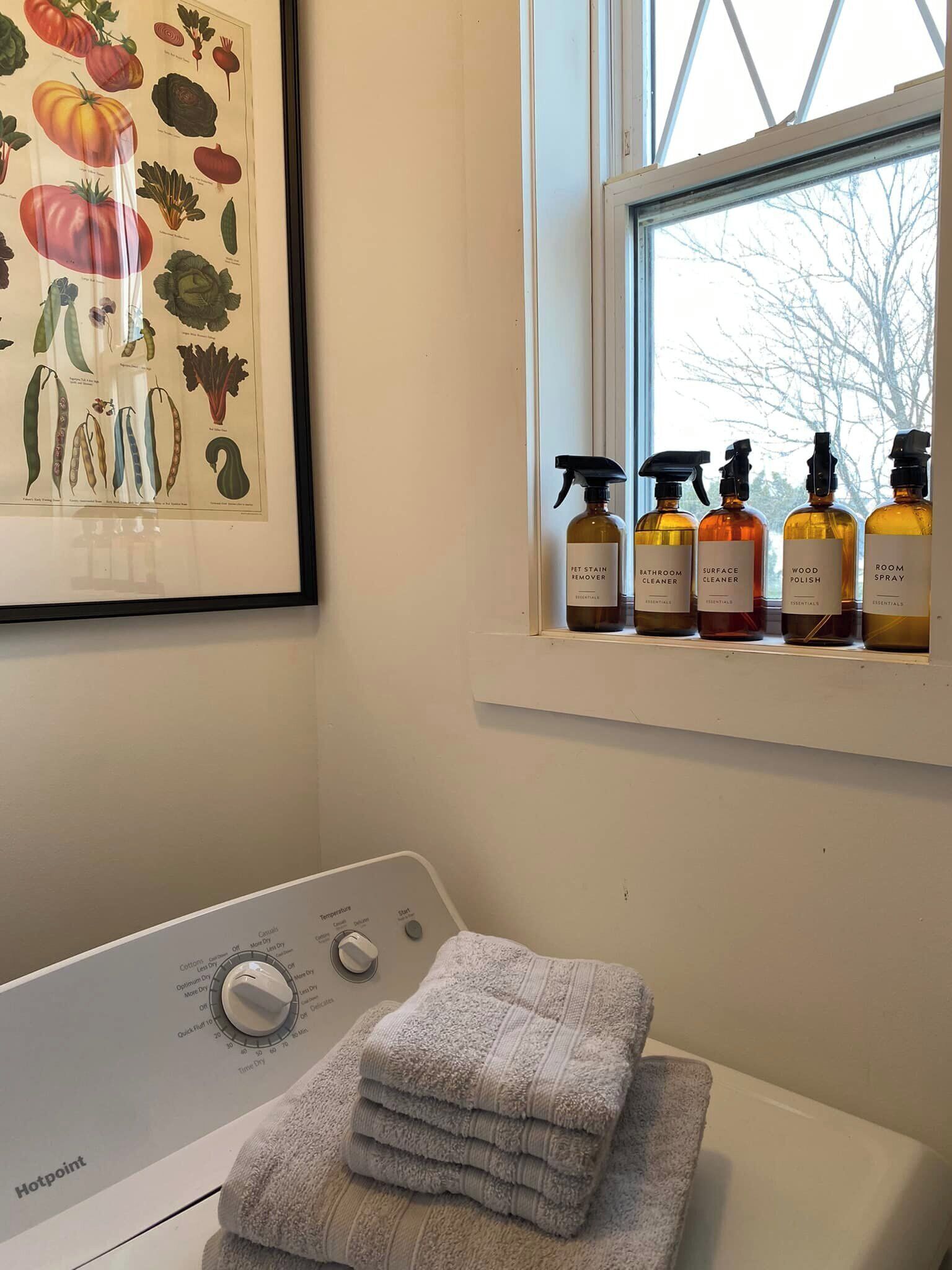 A laundry area with a washing machine, a drying rack, and a shelf with cleaning products.
