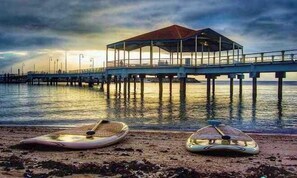 A pier extending into calm waters with a covered structure at the end.
