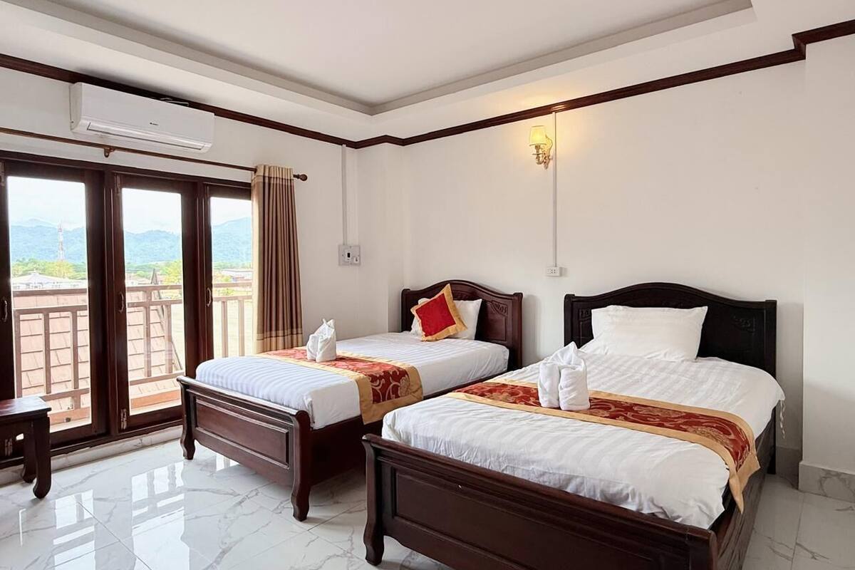 Een hotelkamer met twee bedden, een balkon en uitzicht op de bergen.