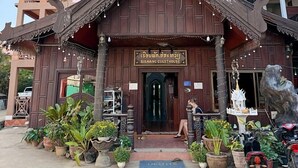 A traditional wooden guesthouse with a signboard, potted plants, and a motorcycle parked outside. - Vangvieng Sisavang Hotel (Vang Vieng)