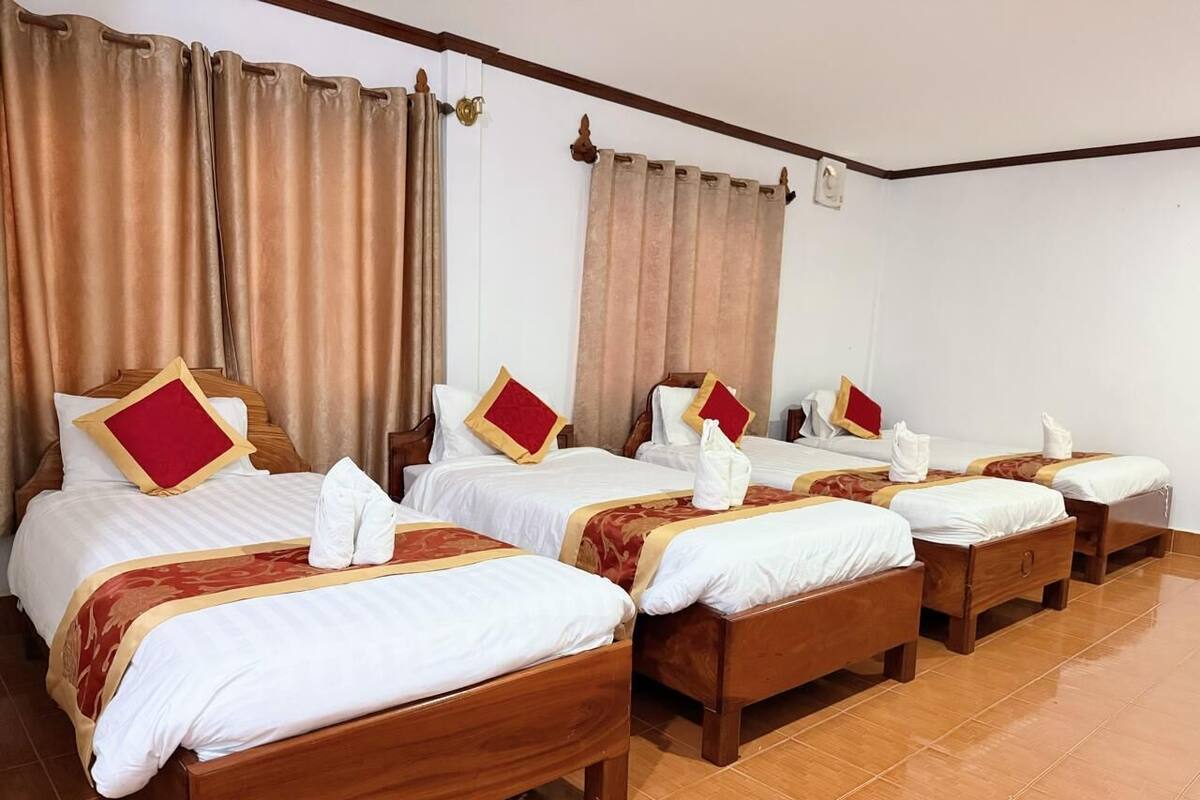 Een hotelkamer met vier houten bedden, elk voorzien van witte lakens en rode kussens.