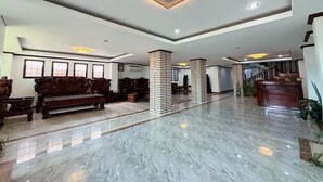 A spacious lobby with a marble floor, wooden furniture, and a staircase leading to upper levels. - Vangvieng Sisavang Hotel (Vang Vieng)