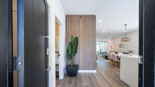 A modern interior with a central potted plant, a wooden partition, and a dining area with chairs and a table. - Perfect Family Getaway, 4BR & Themed Magic (Kissimmee)