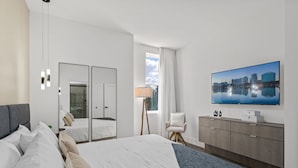 A modern hotel room with a large bed, a television, a wardrobe, and a cityscape view. - Doppio Luxury Home, Themed Magic! (Kissimmee)