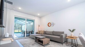 A modern living room with a grey sofa, a wooden coffee table, and a small side table with a plant.