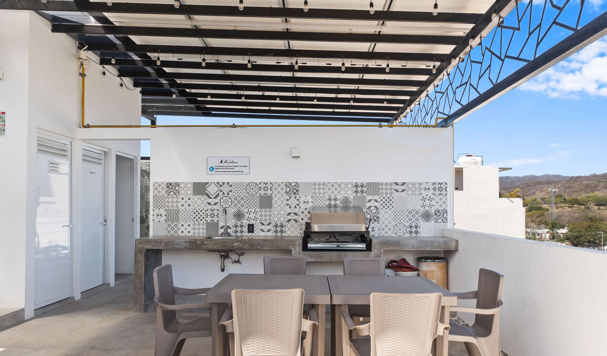 An outdoor patio with a grill, seating, and a patterned wall.