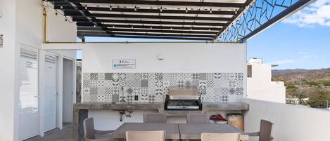 An outdoor patio with a grill, seating, and a patterned wall.