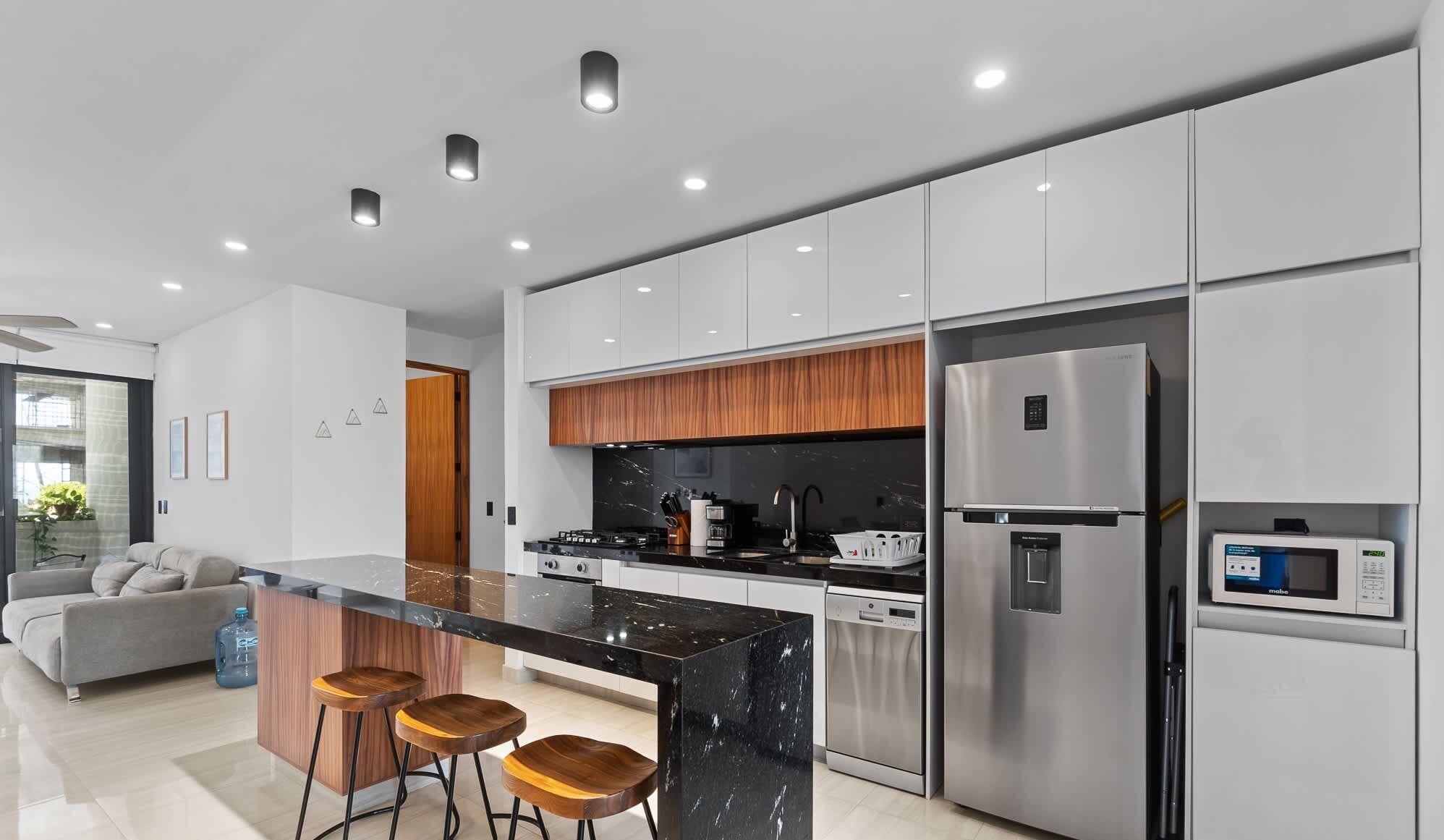A modern kitchen with a central island, stainless steel appliances, and a built-in oven.