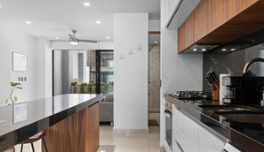 A modern kitchen with a central island, stainless steel appliances, and a view into the dining area. - Avelar: 1BR Near Beach w/ Rooftop Pool & Fast WiFi (Bucerías)