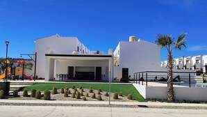 A modern building with a covered entrance, a playground, and a pool area. - Charming 2-bedroom apartment in Los Cabos with WiFi, AC, Swimming Pool and more. (B.C.S.)
