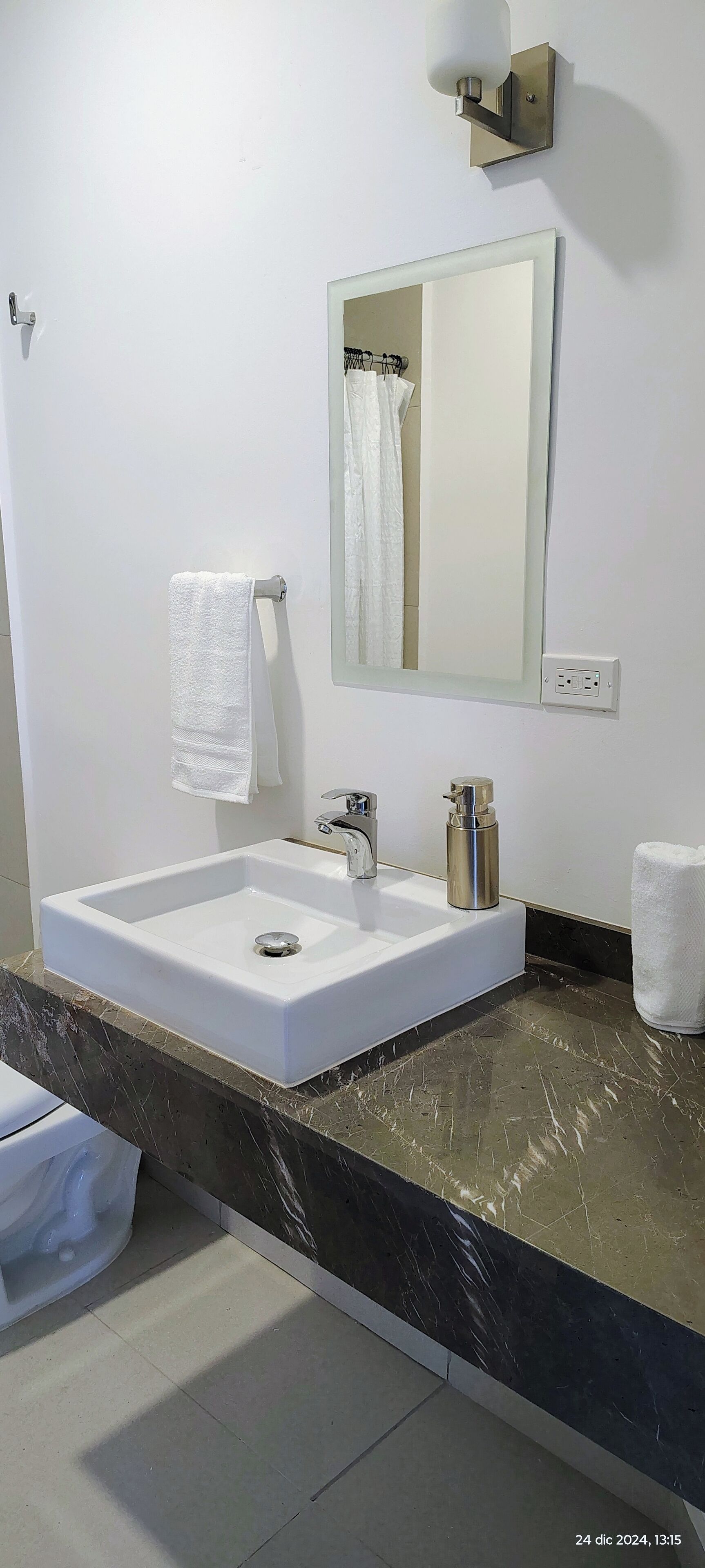 Ein modernes Badezimmer mit Waschbecken, Spiegel, Handtuchhalter und Toilette.