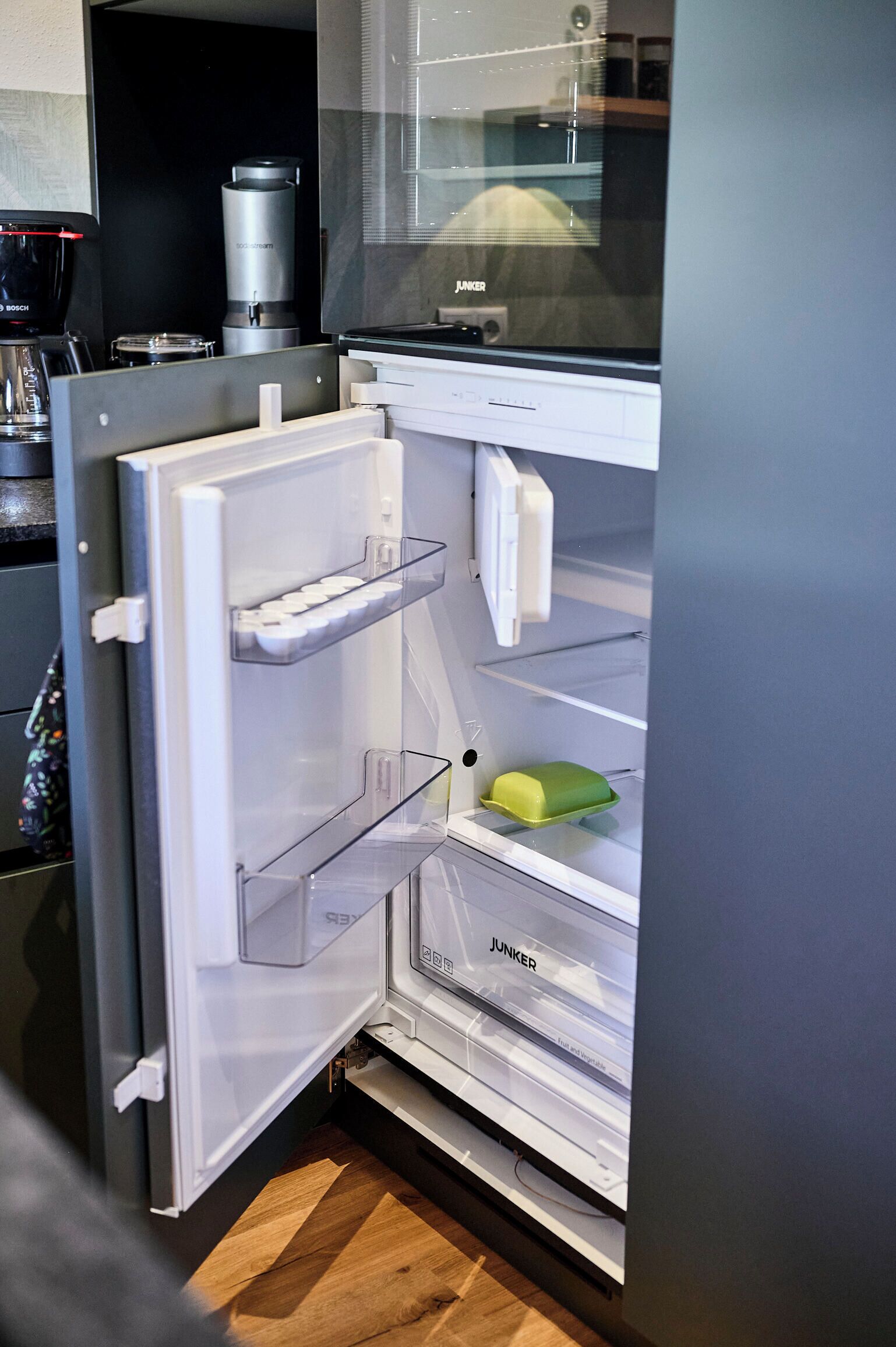 Una cocina moderna con refrigerador integrado, cafetera y microondas.