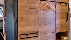 Een houten garderobe met een zwart frame, houten kledinghangers en een plank met dozen.