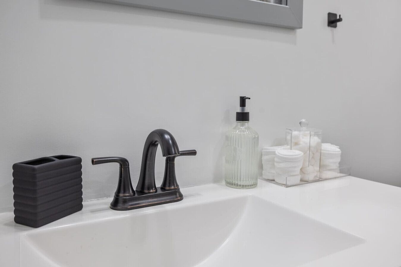 Un lavabo de salle de bain moderne, doté d’un robinet noir, d’un distributeur de savon et d’une pile de serviettes blanches.