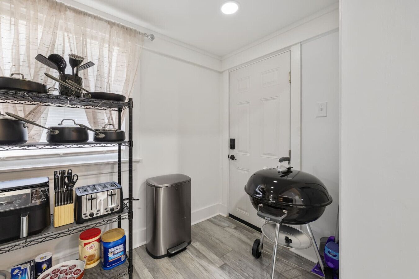 Una cocina compacta con horno empotrado, campana extractora de acero inoxidable y una parrilla portátil.