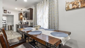 A dining area with a long wooden table, blue placemats, and a central bowl. - Spacious Bungalow Retreat Near Belle Isle, RVA! (Richmond)