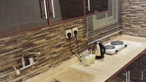 A modern kitchen with a stainless steel sink, a stove, and a countertop with a stone backsplash. - LULUAT ALTHURAYA SERVICED APARTMENT AQIQ (Riyadh)