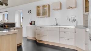 Eine moderne Küche mit weißen Schränken, einer zentralen Kochinsel und einem eingebauten Backofen.