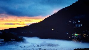 A river with mist rising from the water, surrounded by a mountainous landscape. - Shri Ganga View Guest House (Rishikesh)