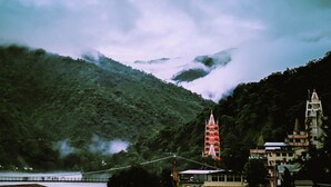 A mountainous landscape with a temple featuring a tiered pagoda and a bell tower. - Shri Ganga View Guest House (Rishikesh)