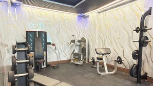Ein Fitnessraum mit Trainingsgeräten, einer Decke mit einer runden Leuchte und einer Wand mit einem wellenförmigen Muster.