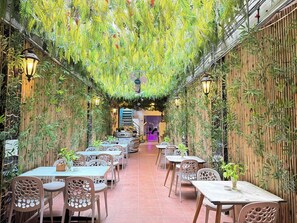 A restaurant with bamboo walls and hanging plants, featuring tables and chairs with a modern design. - Capsule Riverside Saigon (Ho Chi Minh City)