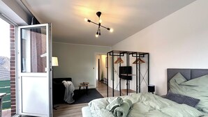 Une chambre moderne avec un lit, un luminaire suspendu, une télévision et une armoire.