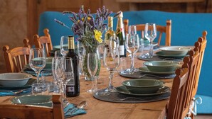 A dining table set with wine glasses, plates, and a bottle of wine, surrounded by chairs. - Finca near Es Trenc Beach (Campos)