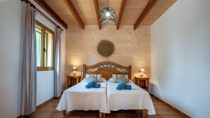 A double room with two beds, wooden headboards, and a stone wall. - Finca near Es Trenc Beach (Campos)