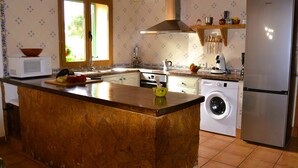 A kitchen with a central island, a washing machine, a microwave, and a refrigerator. - Finca near Es Trenc Beach (Campos)