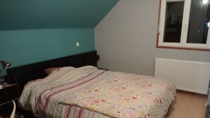 A bedroom with a bed, a nightstand, a table, and a window. - Bed and breakfast in the heart of nature (basic room rate) (Saint-Roch)