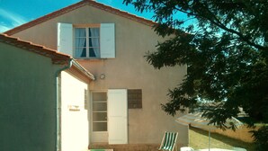 Una casa con un piccolo patio, una porta bianca e una finestra con persiane.