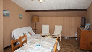 Una stanza accogliente e confortevole con un letto, due poltrone, un tavolo, una lampada, una televisione e un comò.