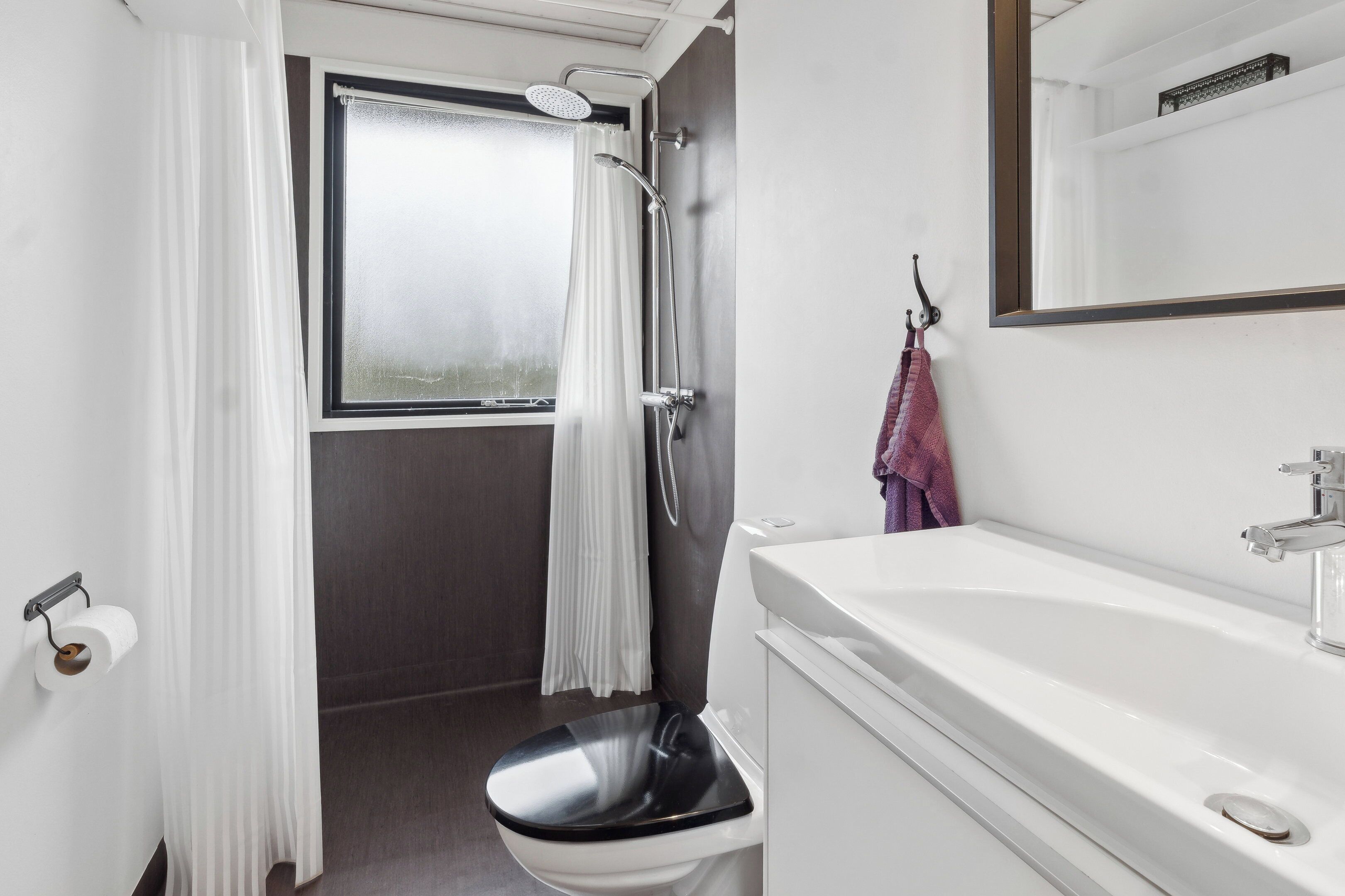 A bathroom with a toilet, shower, and sink.