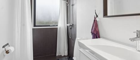 A bathroom with a toilet, shower, and sink.