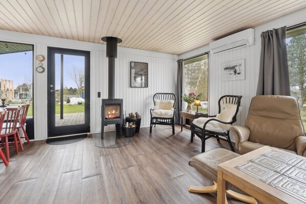 A cozy room with a fireplace, wooden flooring, and comfortable seating.