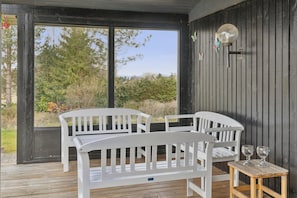 A wooden deck with white furniture and a table with glasses.