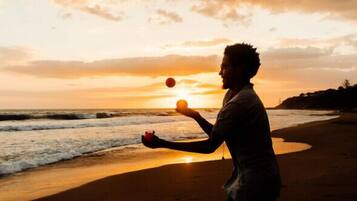Una persona haciendo malabares en la playa al atardecer.