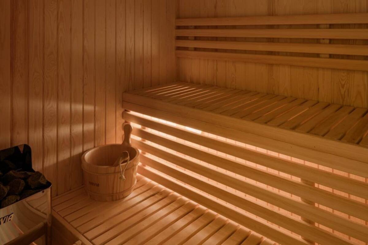 A wooden sauna with benches and a wooden bucket.