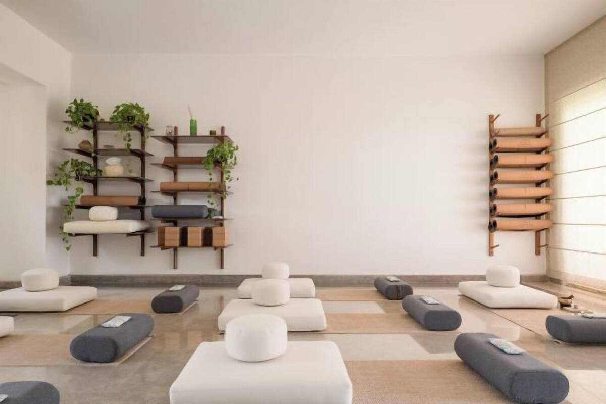 A modern room with multiple seating areas, a wall-mounted plant shelf, and a wooden ladder-like structure.