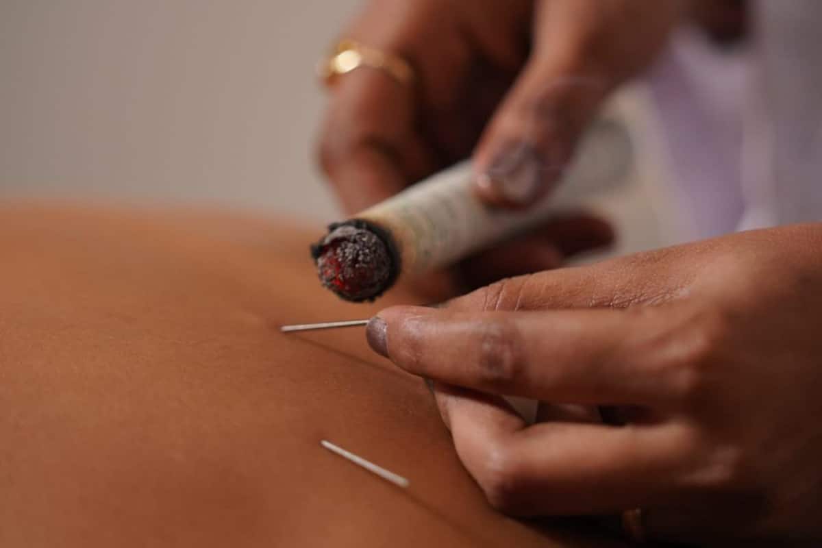 A close-up of a person's hands performing a procedure on a person's skin.