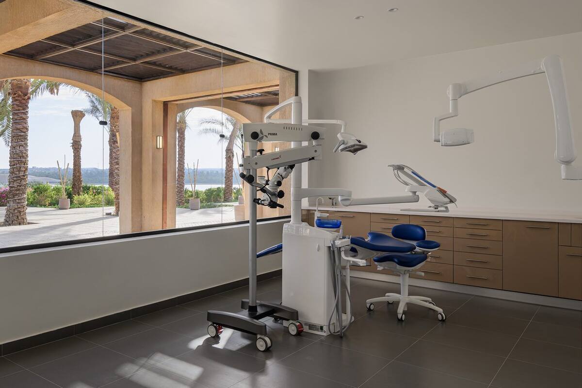 A modern dental clinic with a panoramic view through large windows, a dental chair, and a treatment area.