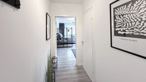 Um corredor com uma cama, uma porta e uma obra de arte emoldurada intitulada 'ARTISAN FLORA'.