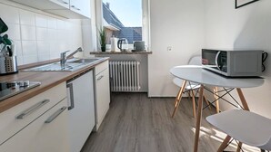 Uma cozinha compacta com pia, fogão e uma pequena mesa de jantar com cadeiras.
