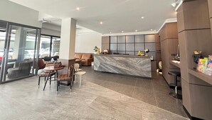 A modern hotel lobby with a marble reception desk, leather seating, and a glass partition. - Leon's Loft House (Patong)
