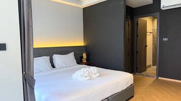 A modern hotel room with a large bed, a nightstand, a decorative golden statue, and a shower area.