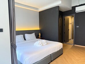 Una camera d'albergo moderna con un letto grande, un comodino, una statua dorata decorativa e un angolo doccia.